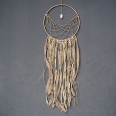 a macrame hanging on the wall with beads and feathers attached to it's sides