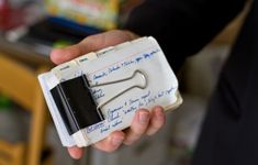 a person holding a small white object with writing on it