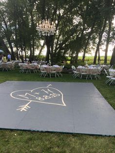 an outdoor dance area with tables and chairs set up for a party in the grass