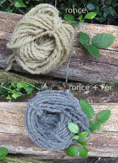 two skeins of yarn sitting on top of a wooden bench next to green leaves