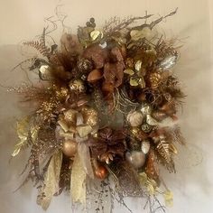 a wreath with gold and silver ornaments hanging from it's centerpiece on a wall