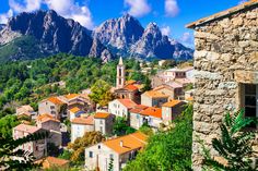 an old village nestled in the mountains with trees and bushes around it, surrounded by greenery