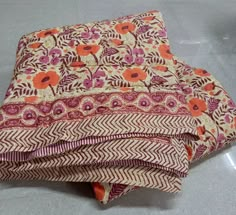 an orange and pink blanket laying on top of a white floor