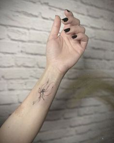 a woman's arm with a small spider tattoo on her left wrist and black nails