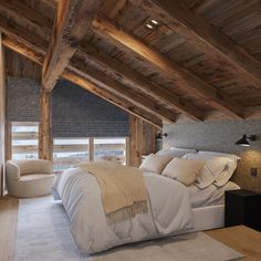 a large bed sitting under a wooden ceiling in a bedroom next to two chairs and a table