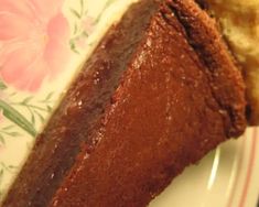 a piece of chocolate pie sitting on top of a flowered table cloth next to a fork