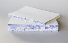 two notebooks sitting on top of each other with blue and white paper covering them