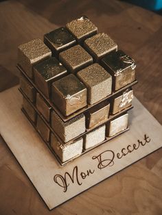 there is a cake made to look like a cube with gold squares on it and the words mon becert