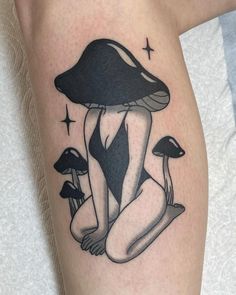 a woman sitting on the ground with mushrooms in front of her leg and an arm tattoo