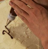 a person is using a drill to make something out of dough with chocolate icing