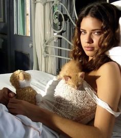 a woman laying in bed with a stuffed animal and teddy bear next to her chest