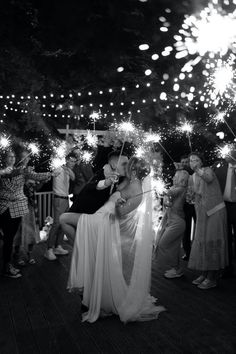 a bride and groom kiss as they are surrounded by their guests with sparklers in the air