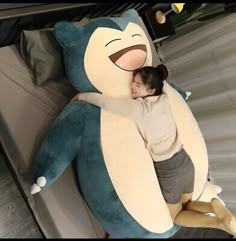 a woman hugging a large stuffed bear on top of a bed