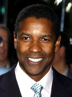 a man in a suit and tie smiling at the camera with other people behind him