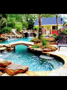 an outdoor swimming pool with waterfall and slide in the back yard, surrounded by landscaping