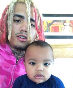 a man with dreadlocks on his head sitting next to a baby