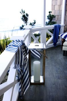 a candle on a porch next to a blue and white striped towel with an ocean view in the background