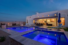 a house with a swimming pool in front of it at night, lit up by blue lights