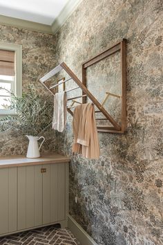 a bathroom with stone walls and wooden cabinetry, towels hanging on the rack in front of mirror