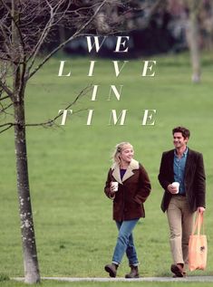 a man and woman walking down a sidewalk next to a tree with the words we live in time on it