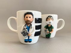 two coffee mugs with figurines in the shape of doctors