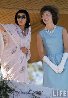 two women in dresses and gloves standing next to each other