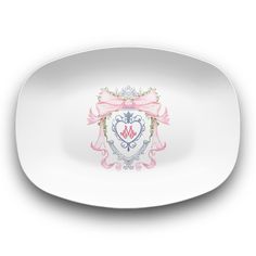 a white plate with an ornate crest and pink ribbon around the edge, on a white background