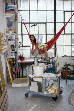 a woman is sitting in a hammock on a table with tools and materials