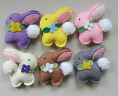 small felt easter bunnies in various colors and sizes with flowers on the ears, sitting next to each other