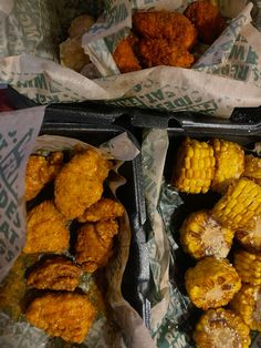 two trays filled with fried corn on the cob and another container full of fried corn