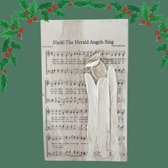 an old sheet music with holly wreaths and white angel wings on it's side