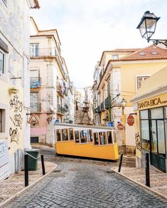 a yellow tram is going down the street