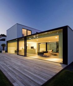 a modern house with large sliding glass doors on the outside and wood decking in front