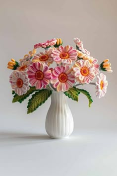 a white vase filled with pink and yellow flowers