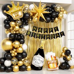 a happy birthday balloon arch with black, gold and white balloons in front of it