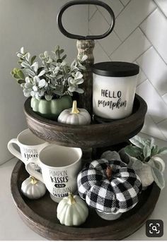 three tiered tray with coffee cups and mugs on it, decorated with black and white pumpkins