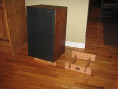 a speaker sitting on top of a hard wood floor next to a wooden box with the word job written on it