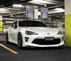 a white toyota sports car parked in a parking garage next to a yellow and green wall