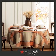 the table is set with dishes and cups on it, along with a vase full of wheat stalks