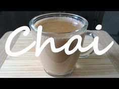 a cup of coffee sitting on top of a wooden tray with the word chai in front of it