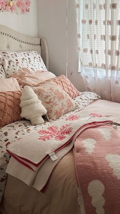 a bed with pink and white comforters in a bedroom next to a large window