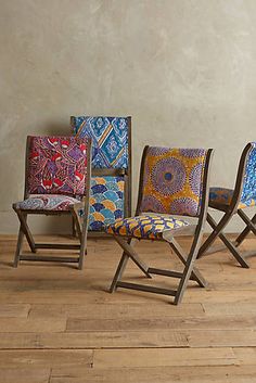 four chairs are lined up against a wall in different colors and patterns, with one sitting on the floor