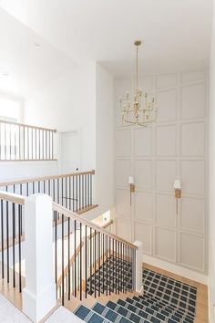 an empty room with stairs and chandelier hanging from the ceiling in front of white walls