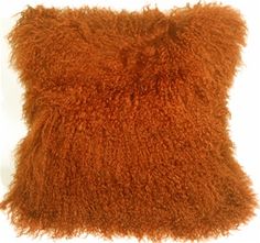 an orange fluffy pillow is shown on a white background and it looks like shaggy fur