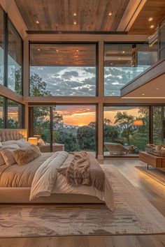 a bedroom with a large bed and lots of windows on the side of it at sunset