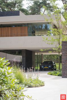 a car is parked in front of a modern building with trees and bushes around it