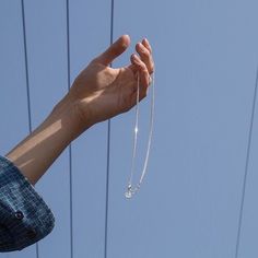 a hand holding a string attached to the side of a building with power lines in the background