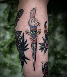 a tattoo on the leg of a person with a rabbit holding a knife