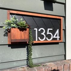 a house number sign mounted to the side of a building with succulents growing out of it