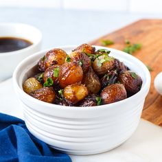 a white bowl filled with cooked potatoes on top of a wooden cutting board